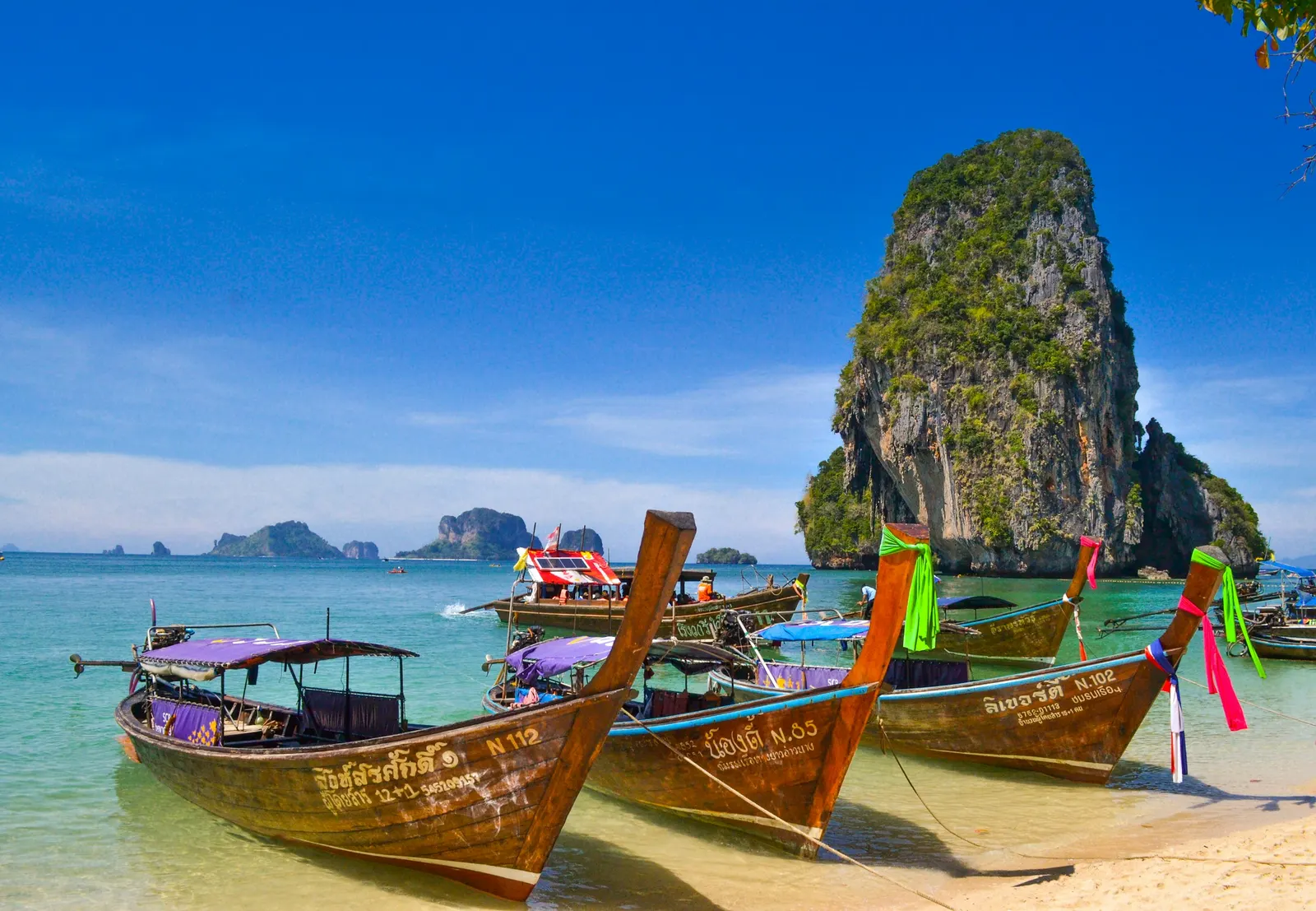 Longtail boats moored on Phra Nang Beach, Krabi, beneath a limestone karst